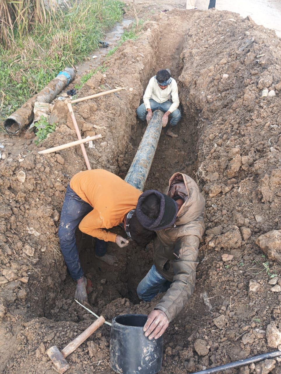 Water supply pipe being laid in trench